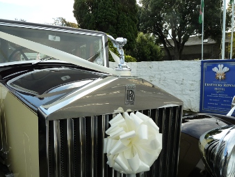 Shows the beautiful ribbon delicately placed on the front grill of the Rolls Royce along with the devine angel